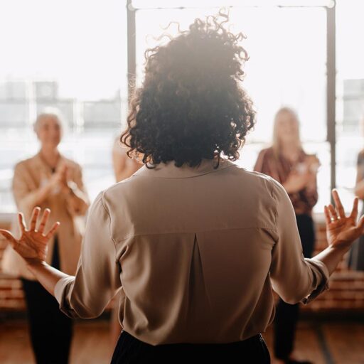 A female employee facing a room with her colleagues giving a presentation on the importance of mental health in the workplace.