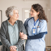 Young female aged worker walking arm in arm with an older female lady - mental health awareness eLearning training courses for aged care and health care
